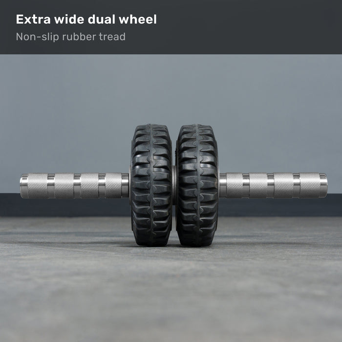 The ABsyidyan Stainless Steel Ab Roller by Bells of Steel USA, featuring extra-wide dual wheels and a 500 lb capacity, stands upright on a gray floor. Text above reads: "Extra wide dual wheel. Non-slip rubber tread.