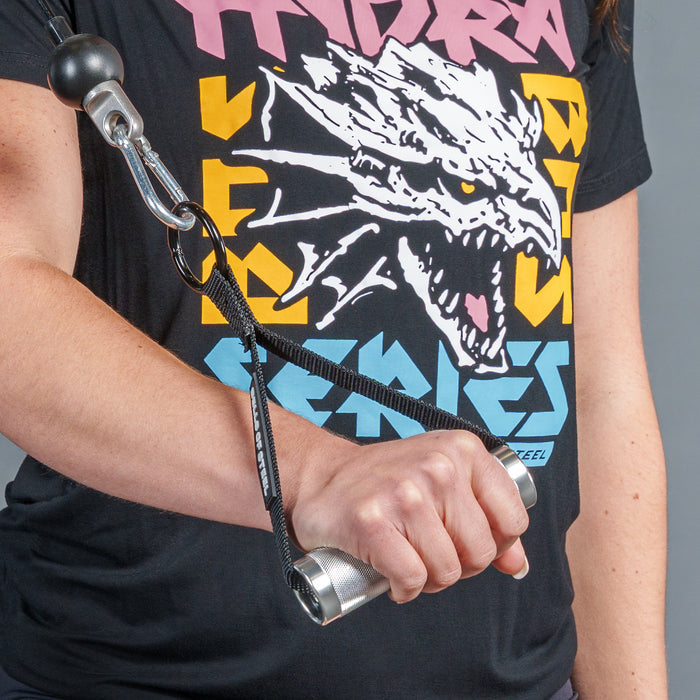 A person holds a Bells of Steel USA Aluminum Handles Pair with Bearings attached to a black strap with a carabiner, while wearing a black T-shirt featuring a roaring dragon graphic and colorful letters, showcasing this versatile gym accessory.