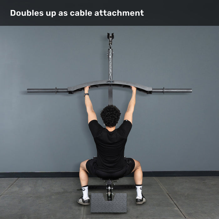 A person sits on a bench facing a gray wall, gripping the Bells of Steel Arch Nemesis Swiss Bar attached to an overhead cable machine. Text above: "Doubles up as cable attachment.