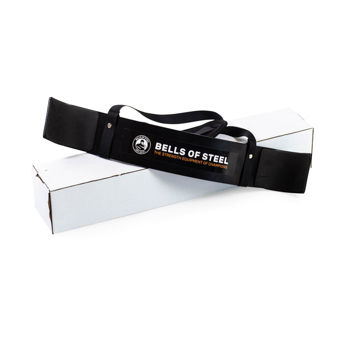 The Bells of Steel Arm Blaster rests atop a long white box, designed to help maintain proper form during bicep curls, shown against a clean white background.