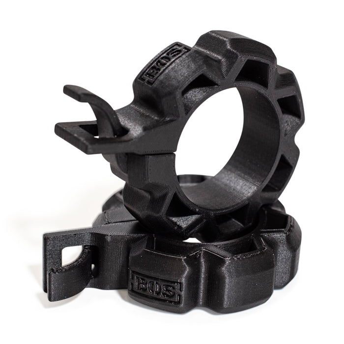 Two black, rugged Barbell Zip Clips - Half Standard (Pair) from Bells of Steel, circular with ridged edges and integrated clips, are stacked together on a white background, resembling standard barbell clips.