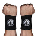 Two fists with wrists facing forward, each wearing Bells of Steel BellGuard Kettlebell Wrist Guards—black guards bearing a circular kettlebell logo and "EST. 2010" in white—essential workout accessories.