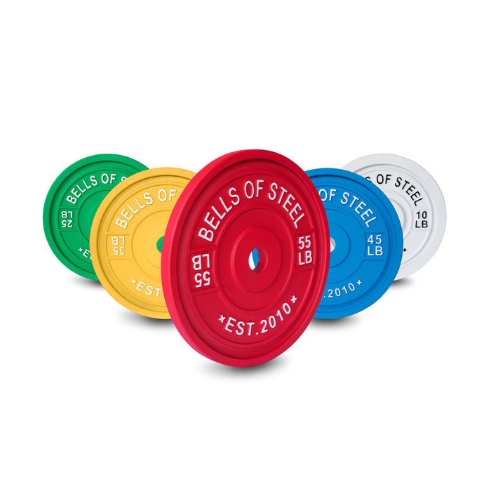 Bells of Steel's Calibrated Powerlifting Plates are displayed in a staggered line, each marked by color and weight: green 25 lb, yellow 35 lb, blue 45 lb, red 55 lb, and white 10 lb—ideal for powerlifting routines.