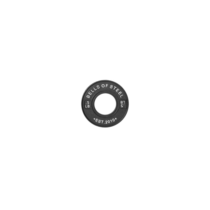 A single black "Bells of Steel" 5 LB calibrated powerlifting plate, part of the collection established in 2010, rests against a plain white background, highlighting its durability and precision.