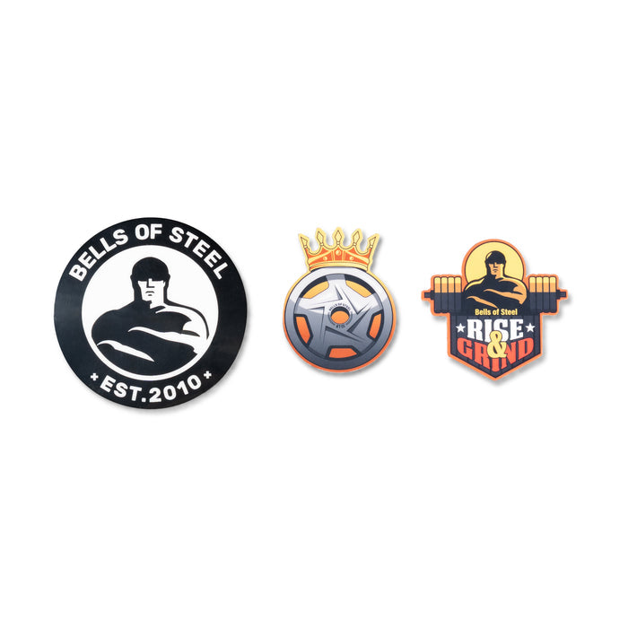 The Bells of Steel USA Die-Cut Sticker Upgrade/Sticker Pack includes three designs: a muscular figure with “Bells of Steel EST. 2010,” a crowned weight plate, and “Rise & Grind”—ideal for gym decals or motivation.