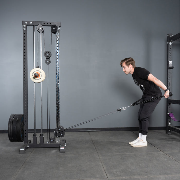 A man in athletic wear uses the Bells of Steel Extra Long Tricep Rope Extension (137cm) in a gym, leaning forward while pulling the cable attachment for a resistance exercise.