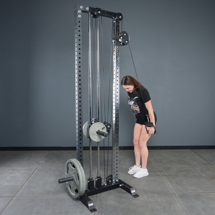 A woman in athletic wear uses the Bells of Steel Fat Bar – Single D Handle on a cable machine for triceps in a gym with gray walls, elbows at her sides and looking down to boost grip strength.