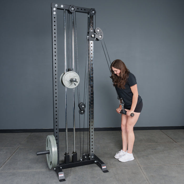 A woman in athletic wear uses the Bells of Steel Fat Bar - Straight Handle Bar to perform a tricep pushdown on a cable machine, standing slightly bent forward with arms fully extended.
