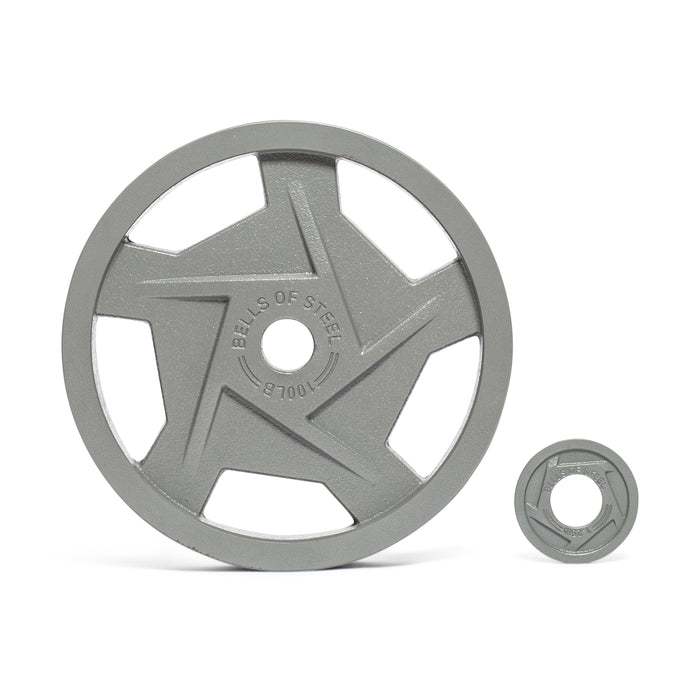 Two steel weight plates are displayed against a white backdrop. The larger one features a star design with "Bells of Steel" engraved, showcasing its ergonomic design. The smaller Gray Mighty Grip Olympic Weight Plate by Bells of Steel has a centered hole for improved grip during workouts.
