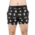 A person wears Bells of Steel Gym Shorts featuring white logos, text, and graphic designs while standing against a white background.