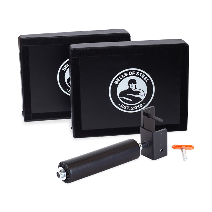 The Hydra Nordic Curl Package by Bells of Steel, shown on a white background, includes two black foam deadlift pads with the brand logo, a split squat attachment with a padded bracket, and an orange adjustment tool.