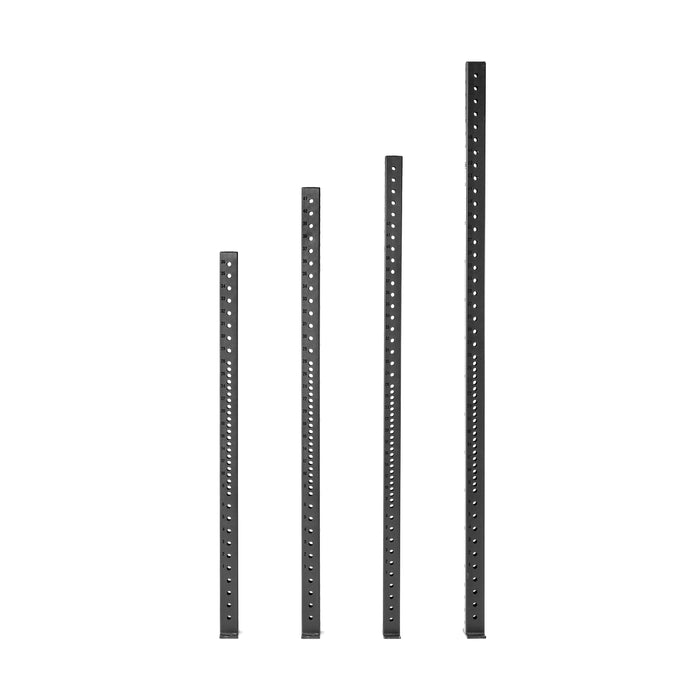 Four black Hydra Vertical Uprights by Bells of Steel are positioned side by side against a white background. Each upright features multiple evenly spaced holes along its length, perfect for accommodating rack attachments.