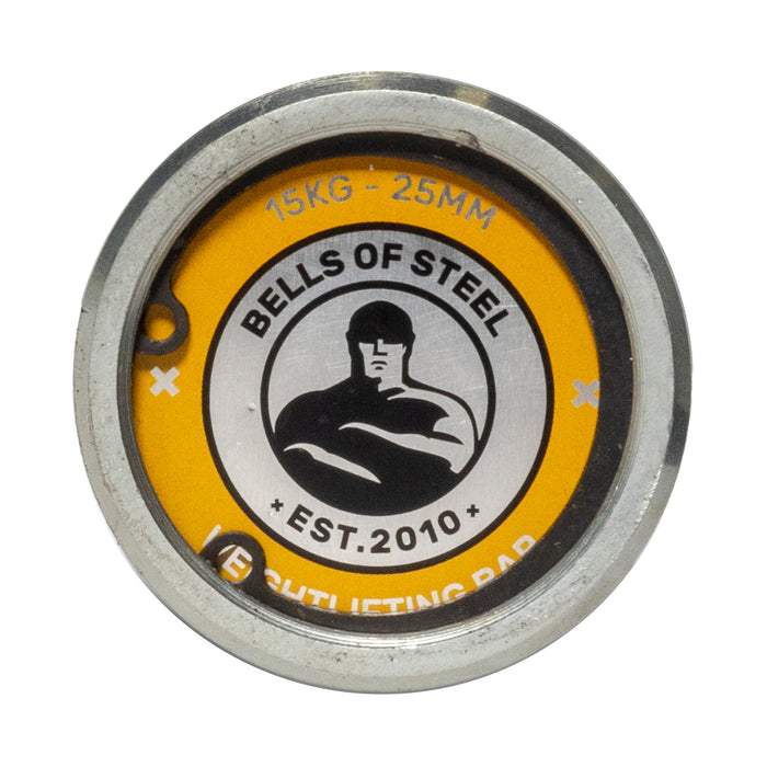 Close-up of a round metal plate on a yellow background showing the "Bells of Steel" logo, "EST. 2010," and "15KG - 25MM"—designed for the Juno Bar - Women’s Utility Bar by Bells of Steel, ideal for small hands.