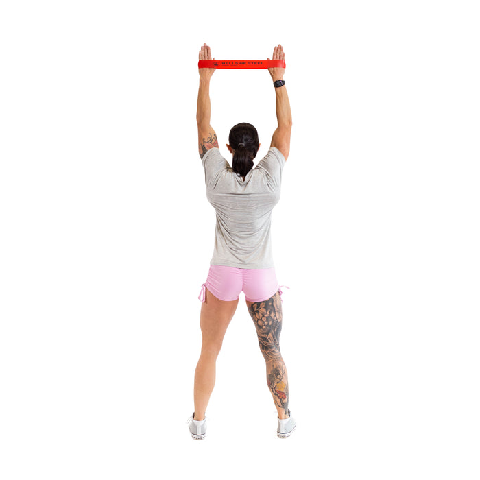 A person holding a red Mini Band by Bells of Steel, one of the essential gym accessories for effective workouts.