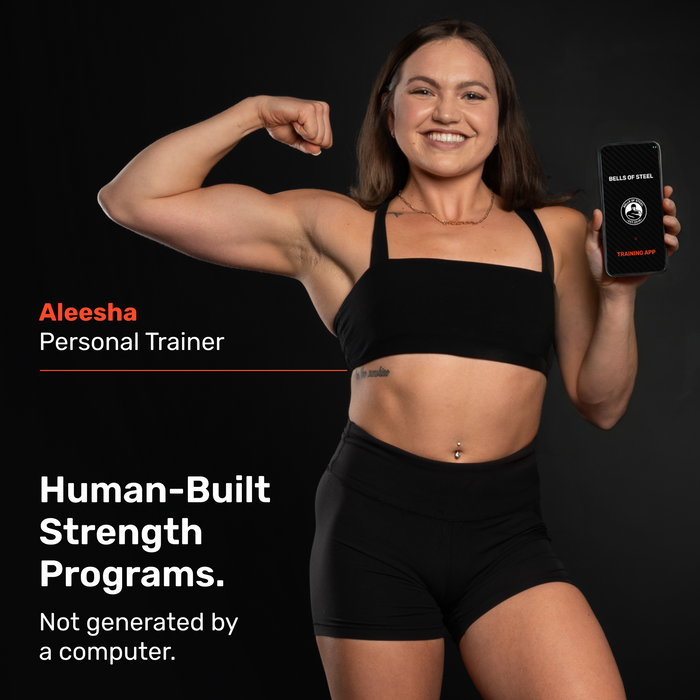 A smiling female trainer in athletic wear flexes her arm and holds a phone showing a fitness app. Text: "Bells of Steel Online Coaching – Personalized coaching with human-built strength programs.