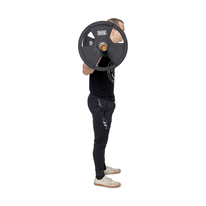 A person in a black t-shirt and dark pants is shown lifting a barbell using Bells of Steel's Rubber Coated Iron Weight Plates, marked "45 lbs," known for their durable virgin rubber coating.
