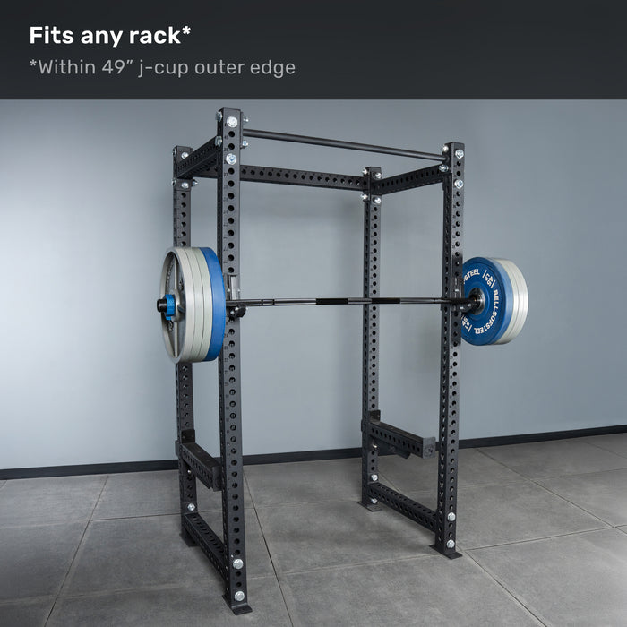 A Bells of Steel Short Rackable Barbell rests on j-cups of a power rack. Text above states, "Fits any home gym rack* *Within 49” j-cup outer edge." The rack is positioned on a tiled floor against a plain gray wall.