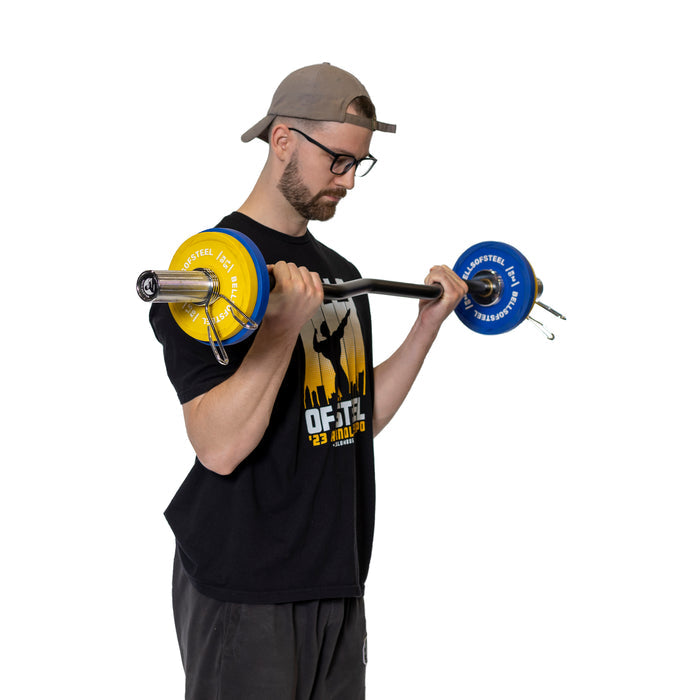 A person in a black shirt and cap performs a barbell curl with polished chrome Olympic barbell sleeves, featuring Bells of Steel Spring Collars. The blue and yellow plates are secure on the barbell against a plain white backdrop, highlighting the sleekness of the scene.