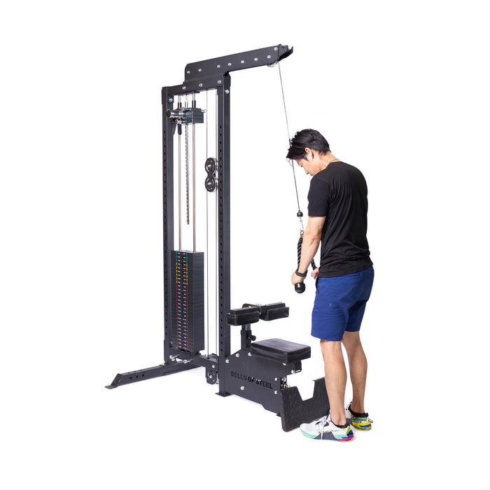 A person stands facing the weight stack, preparing for a tricep workout with the Bells of Steel Tricep Rope Extension against a white background.