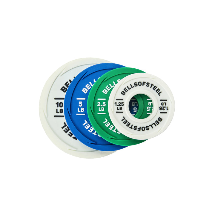 Bells of Steel Urethane-Coated Change Plates—white (10 lb), blue (5 lb), green (2.5 lb), and white (1.25 lb)—are stacked and fanned out, each labeled with its weight and brand for easy identification during training.