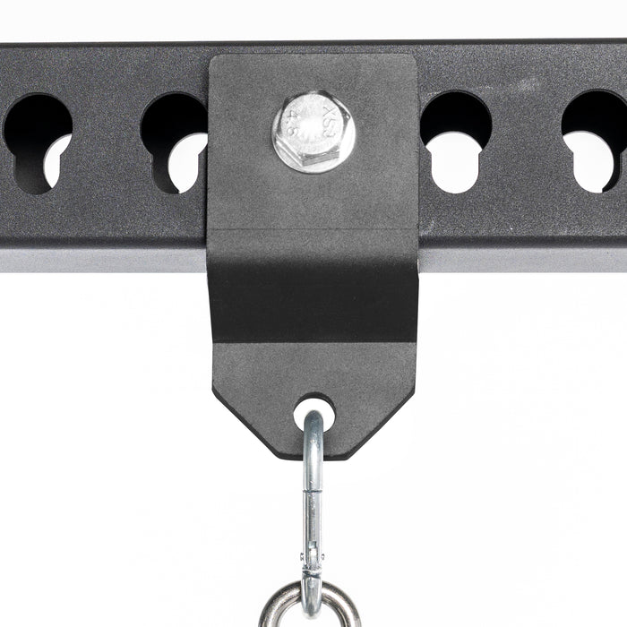 Close-up of the Bells of Steel Utility Shackle Rack Attachment in black metal, securely fastened to a perforated metal bar with a large bolt, featuring a metal hook hanging from the bracket—perfect for mounting gym equipment or organizing home gym accessories.