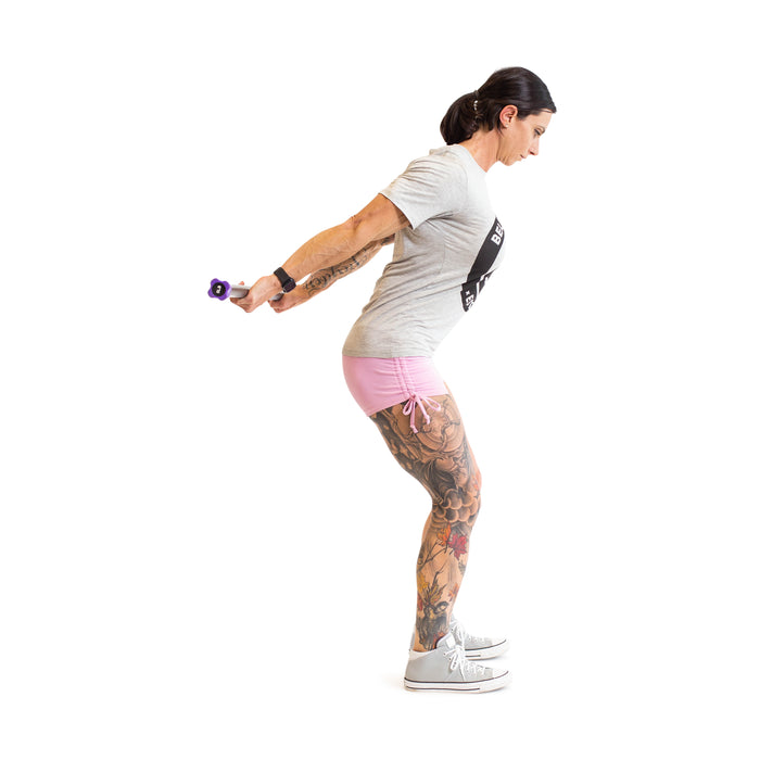 An individual with tattoos in a gray t-shirt, pink shorts, and sneakers displays fitness gear by holding Bells of Steel Weighted Workout Body Bars against a white background, bending forward slightly with both arms extended back.